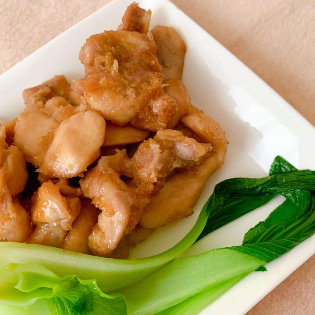 スクエア型の皿に乗った鶏の炒め物とチンゲン菜
